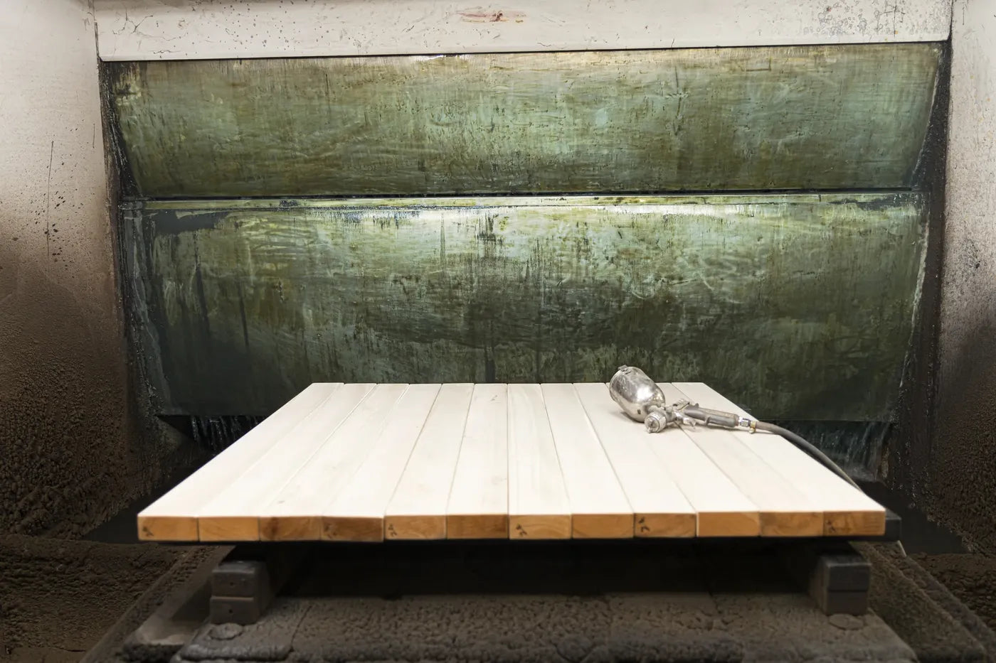 A panel resting in the finishing booth with a spray gun