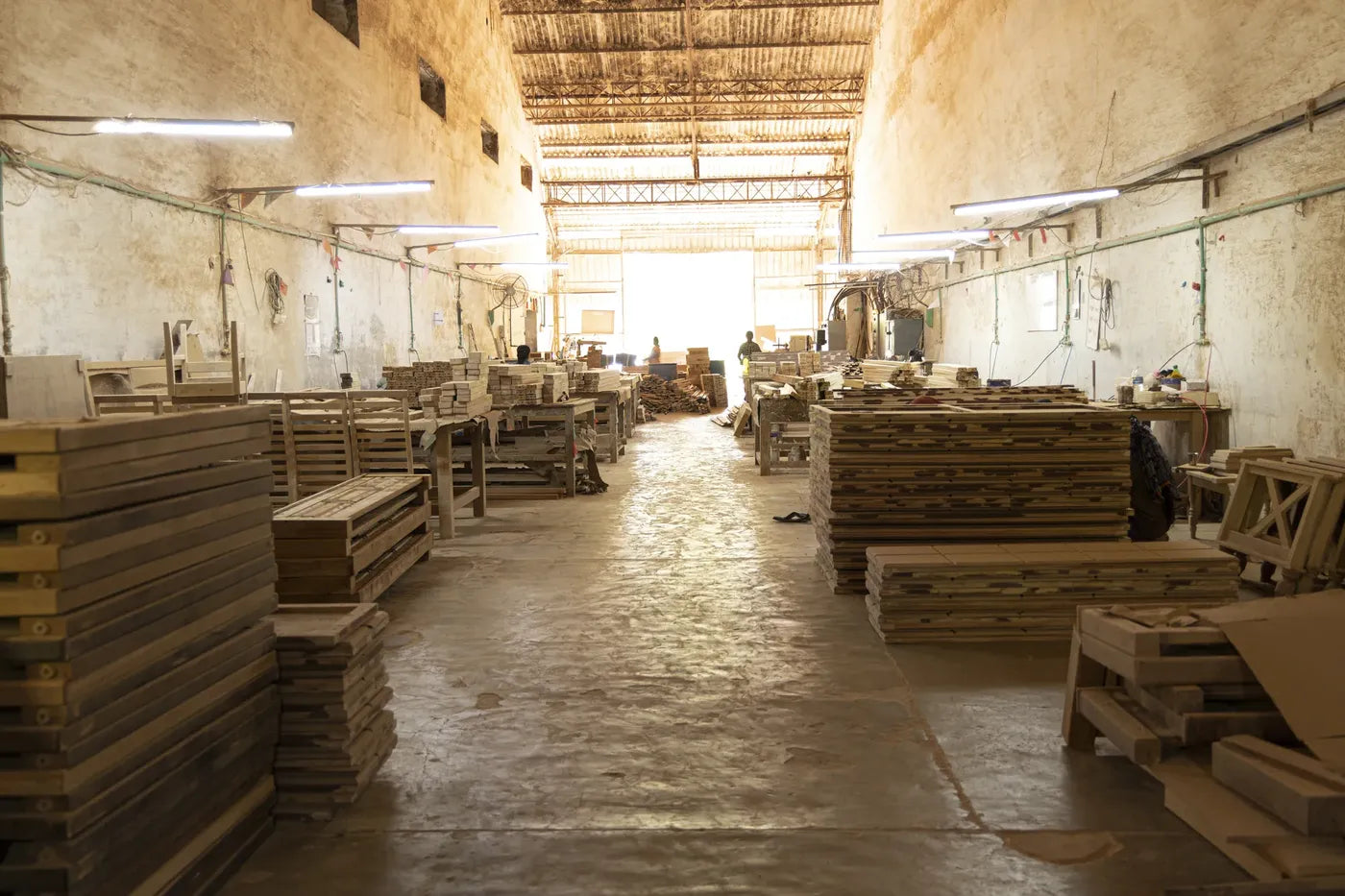 The main hall of the Kalingaa workshop, with workbenches and stacked timber