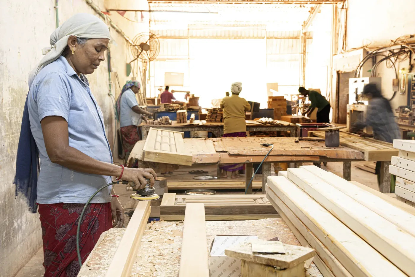 A craftswoman hand-sanding a timber frame